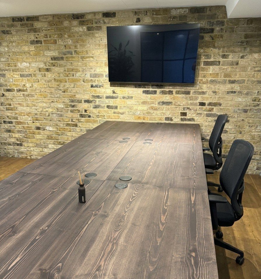 Dark solid wood desk run against a brick wall in an office