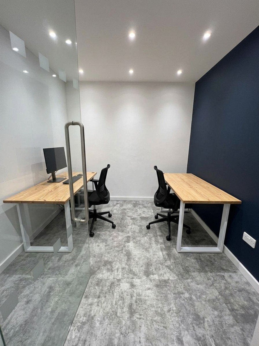 Two pine desks with white legs in a small office
